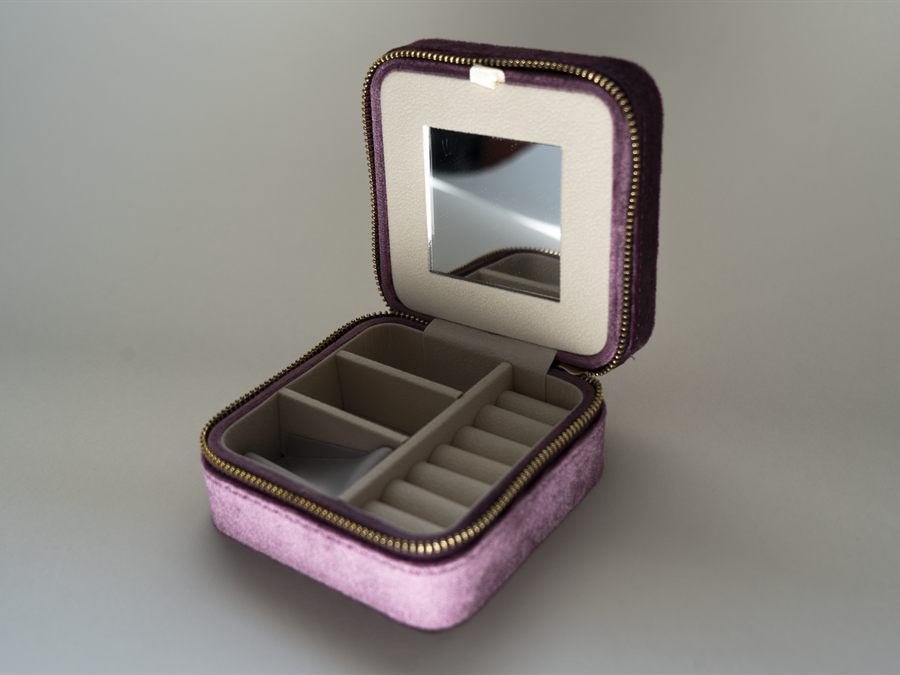 An open purple velvet jewellery case with a mirror, ring rolls and compartments