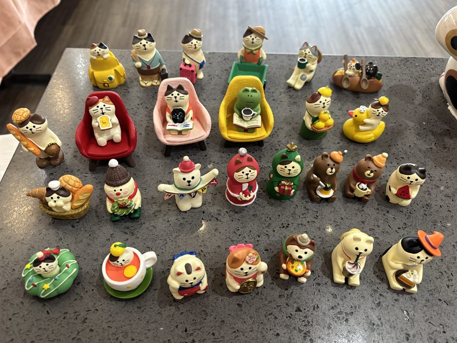 A tableful of small painted cat and bear figurines in hats, aprons and costumes