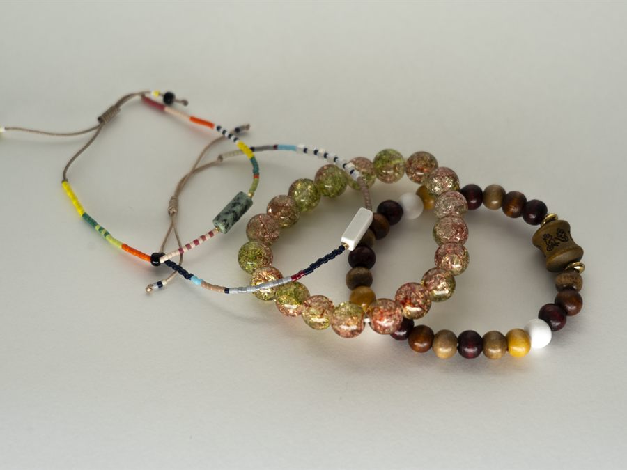 Three beaded bracelets: crackle glass, polished wood, and a fine seed-bead strand